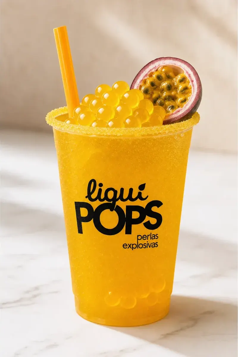 Vaso de minuta de maracuyá con borde escarchado y perlas explosivas amarillas encima, con sorbete amarillo
